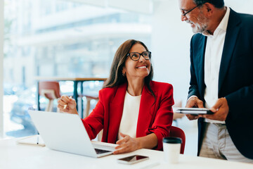 Smiling businesswoman in red blazer interacting with colleague during a work discussion