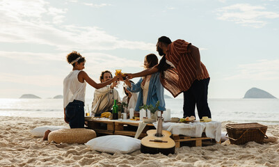 Friends enjoying a picnic on the beach with food and drinks