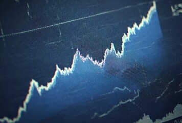 Macro close-up of a financial graph showing an upward trend against a dark blue grid, conveying market analysis and growth visualization