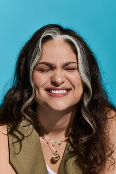 Stylish woman smiles radiantly in vibrant blue setting showcasing her unique beauty