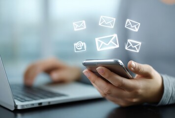 Close-up image shows a person using a smartphone with email icons floating above. There is a laptop in the background
