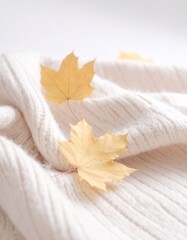 Yellow autumnal leaves on pastel beige knitted fabric blanket.