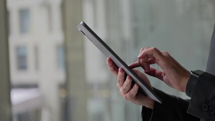 Businessman uses digital tablet by the window in his office - Powered by Adobe