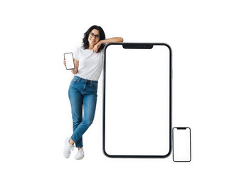 Young woman with dark wavy hair and glasses poses beside large smartphone screen transparent background