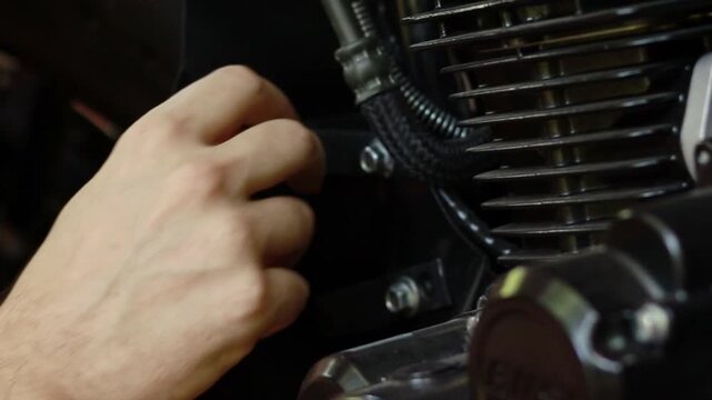 Closeup footage of mechanic's hand performs maintenance on a motorcycle engine