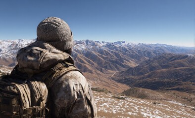A distant mountain range vista observed by a person with a beanie wearing a camouflage patterned jacket on a snowy plateau under a clear sky