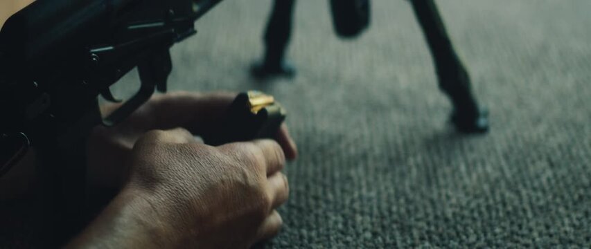 Shooter holds rifle magazine while preparing to load bullets on shooting range