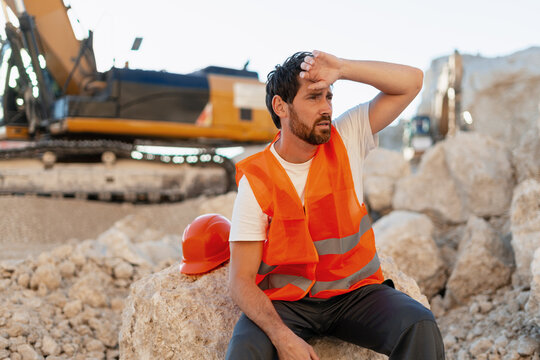 Tired construction worker wiping sweat from forehead in quarry