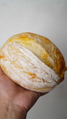 Hands holding whole double cheese sourdough bread on a white background.