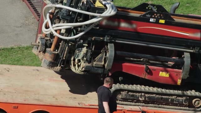 A modern horizontal drilling machine for laying water pipes and electric cables is driven off a lowboy semi-trailer, industry, background