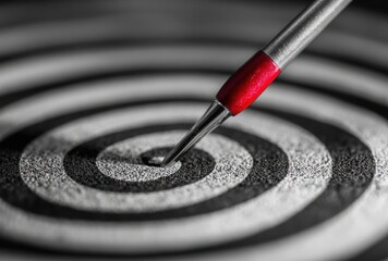Sharp, red-tipped dart pierces a grayscale target's center. Concentric rings guide focus. Aim, precision and accuracy prevail in this striking image