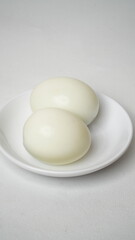 Peeled boiled eggs served on a white plate with a white background