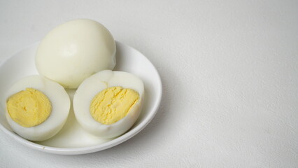 Peeled boiled eggs served on a white plate with a white background