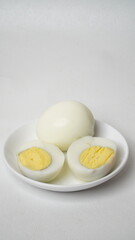 Peeled boiled eggs served on a white plate with a white background