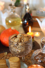 Lit candles, cookies, chocolate, nuts, tea, wine, pumpkins, books, reading glasses and autumn leaves on the table. Autumnal hygge at home. Selective focus.