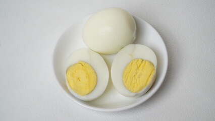 Peeled boiled eggs served on a white plate with a white background