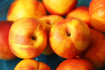 Fresh nectarines closeup with vibrant colors. Juicy ripe fruits on blue background. Natural healthy summer harvest. Sweet vegetarian snack. Organic orchard fruit for diet and nutrition lifestyle.