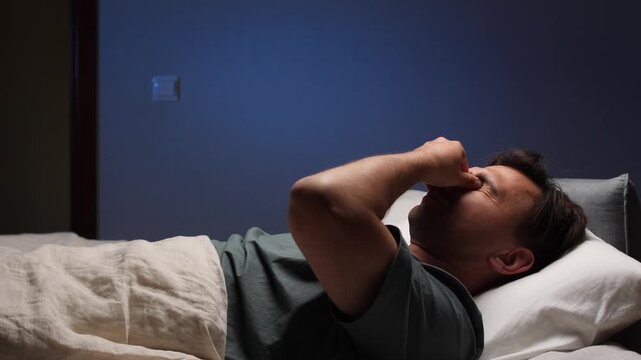 A man takes off his glasses before going to bed and rubs his tired eyes