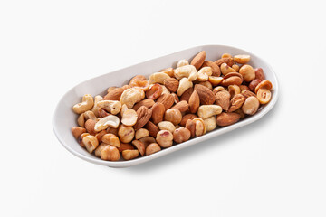 Healthy assortment of mixed nuts including almonds, cashews, hazelnuts in white oval plate isolated on white background