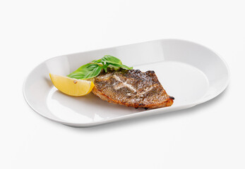 Juicy grilled sea bass fillet served with a fresh lemon wedge and basil leaves on a white plate, isolated on white background, healthy seafood meal for restaurant menu or home cooking