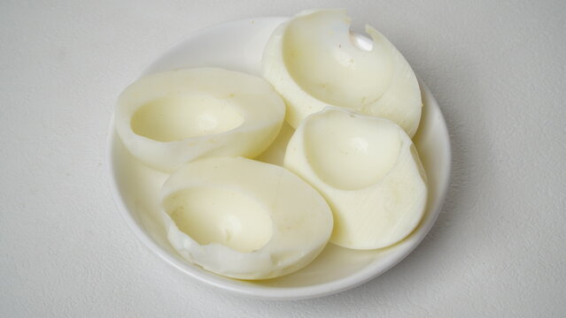 Peeled boiled eggs served on a white plate with a white background