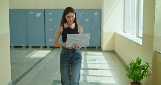 Indian young gen z busy woman lady in hold laptop hand look screen check new email notes walk campus place. Teen girl female pupil use device do exam study online e learn work skill data day time