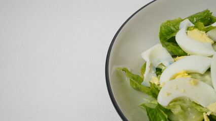 A serving of salad consisting of sliced ​​romaine lettuce, Japanese cucumber (kyuri), and boiled egg  without salad dressing served on a white plate and white background.