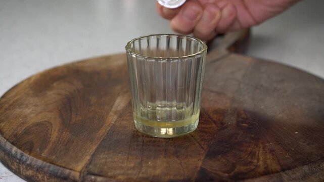 Measuring oil on digital scale for homemade lip balm. DIY natural cosmetics process with organic skincare ingredients, eco-friendly beauty preparation, and handcrafted apothecary style.