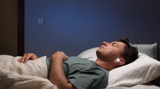 man puts on earplugs in a noisy apartment to sleep peacefully 