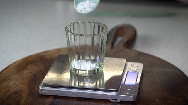 Measuring butter and wax on digital scale for homemade lip balm. DIY natural cosmetics process with organic skincare ingredients, eco-friendly beauty preparation, and handcrafted apothecary style.