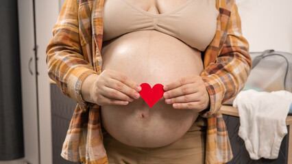 Pregnant woman holding red heart shape and feel love for unborn baby in belly. Awaiting for baby....