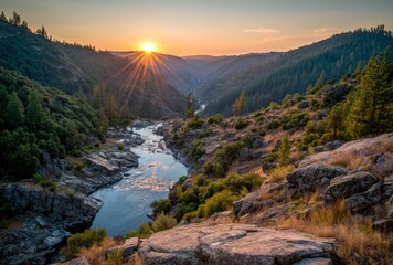 Serene view river winds through a lush valley at sunset, silhouetting trees as golden sunbeams burst over the horizon from behind distant mountains