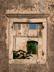 Close-up of a weathered, cracked and broken window frame and stone wall of a derelict school building in Donji Stoliv, Montenegro, damaged in the 1979 earthquake.