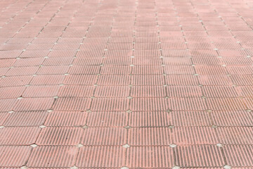 red interlocking pavement tile grid with vertical grooves and small white joints, uniform walkway background