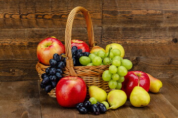 Cesto in vimini co uva bianca , uva nera , mele e pere