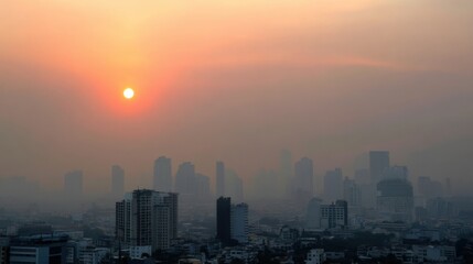 Fototapeta premium City skyline at sunset, enveloped in dense smog, creates dramatic silhouette against orange sky. atmosphere evokes sense of mystery and urban life