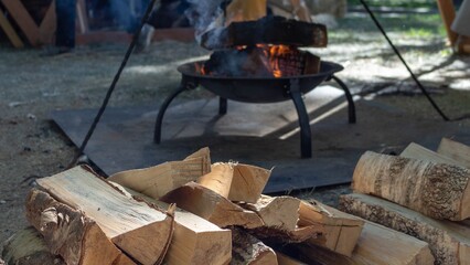 A cozy campfire scene with stacked firewood and a burning fire pit in the outdoor forest...