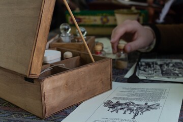 A mysterious wooden box with old medical tools and handwritten documents on a dark surface