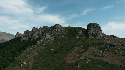 Rocky peaks of Babin Zub mountain in Stara Planina National Park, Serbia, rise above green forests under a blue sky. Aerial view from drone