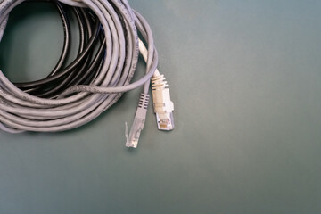 A white and gray cable rj45 is laying on a green surface