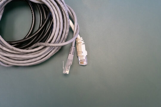 A white and gray cable rj45 is laying on a green surface