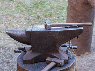 A black iron anvil with a hammer and other tools on top of it