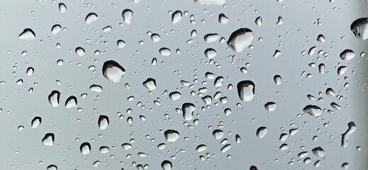 Water Bubble On The Glass. Water droplets on the car window. Rain falls through the car window parked outdoors. Rain transparent drops flow down the car glass. Water droplets scatter on glass window
