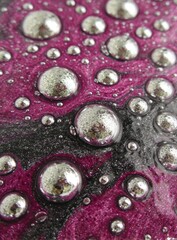 Close-up of shiny, silver droplets on swirling dark pink, gray, and black textures; creating a mesmerizing, abstract, liquid-like appearance