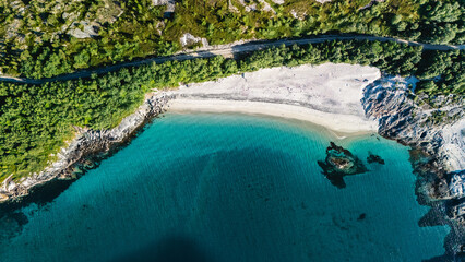 Tranquil waters meet white sandy shores at Bognes, Lofoten, a breathtaking coastal retreat in Norway. Lush greenery lines the beach, perfect for relaxation and exploration.