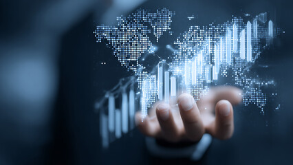 Hand holding glowing digital world map with financial bar graphs, representing global business and data technology.