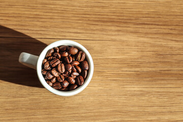 top view image of a coffee cup and a handful of beans on a simple wooden background. top view coffee minimalist. morning coffee aesthetic flat lay