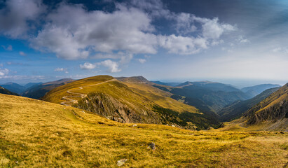 A solo traveler experiences a breathtaking autumn day in the wild Carpathian Mountains, near Lake Galcescu, in the Parang Mountains of Romania, where vibrant fall colors meet rugged peaks
