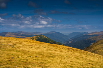 A solo traveler experiences a breathtaking autumn day in the wild Carpathian Mountains, near Lake Galcescu, in the Parang Mountains of Romania, where vibrant fall colors meet rugged peaks