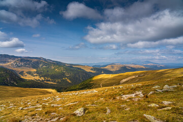 A solo traveler experiences a breathtaking autumn day in the wild Carpathian Mountains, near Lake Galcescu, in the Parang Mountains of Romania, where vibrant fall colors meet rugged peaks